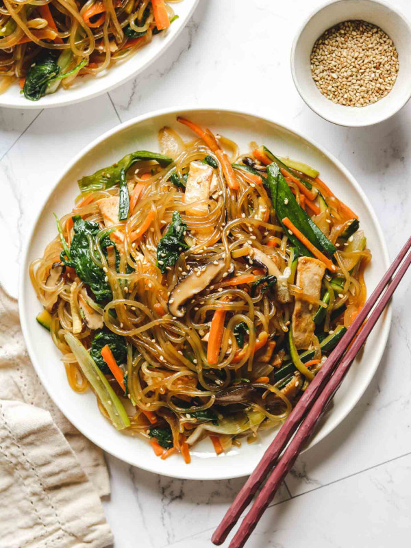 vegan japchae korean glass noodles on a white plate