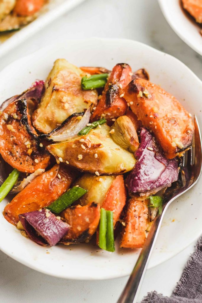 maple roasted root vegetable in a bowl with sesame seeds and green onions