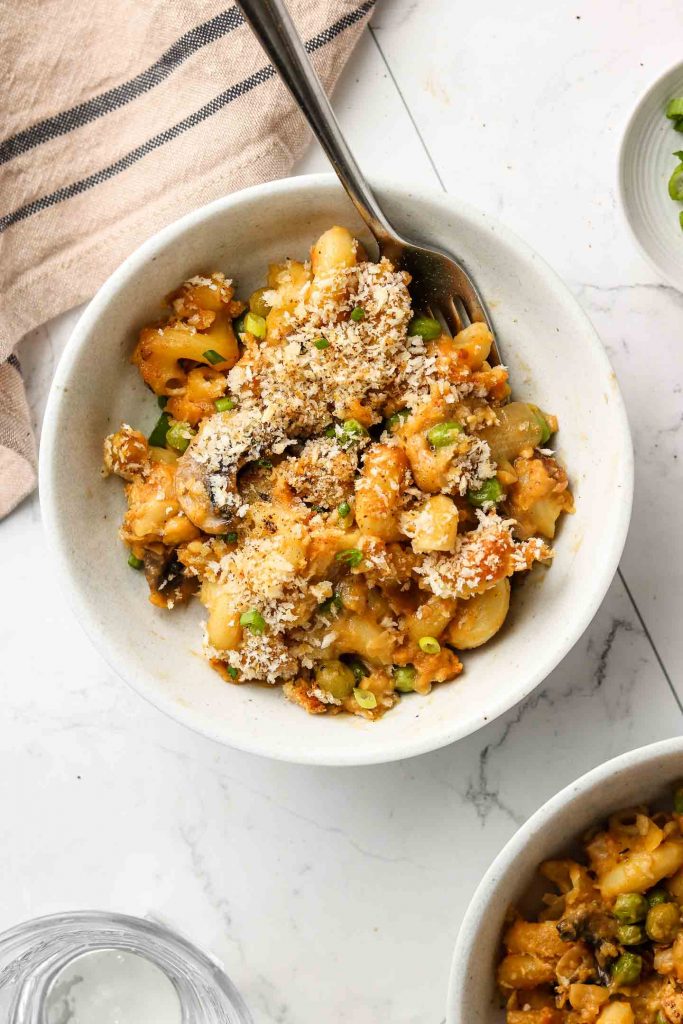 vegan tuna noodle casserole in a bowl with breadcrumbs and a fork