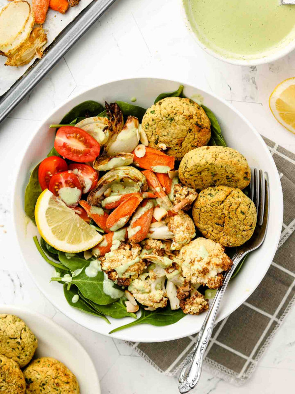baked falafel balls on a warm salad with cilantro sauce on top