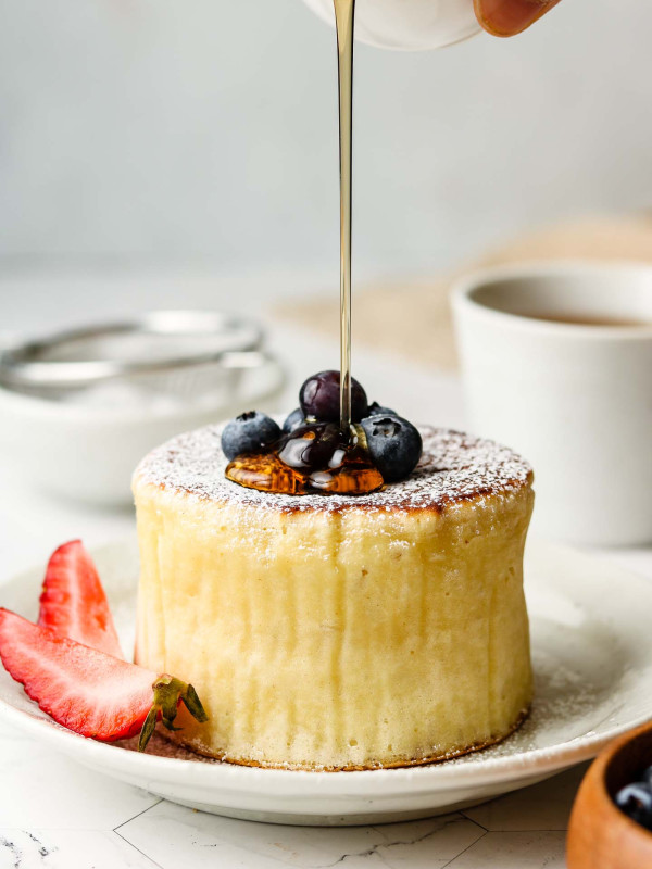 souffle pancakes with blueberries on top and maple syrup pouring
