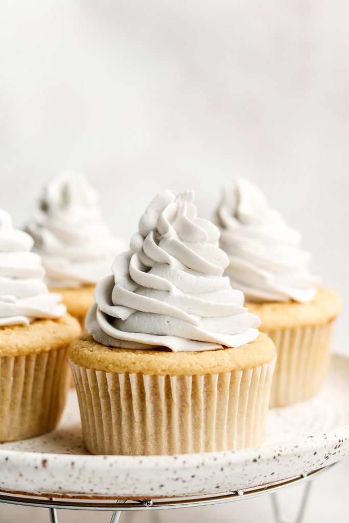 vanilla cupcakes with coconut whip cream frosting on a white plate
