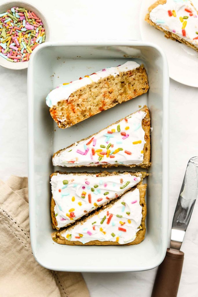 vegan funfetti cake cut into triangle slices in a blue loaf pan