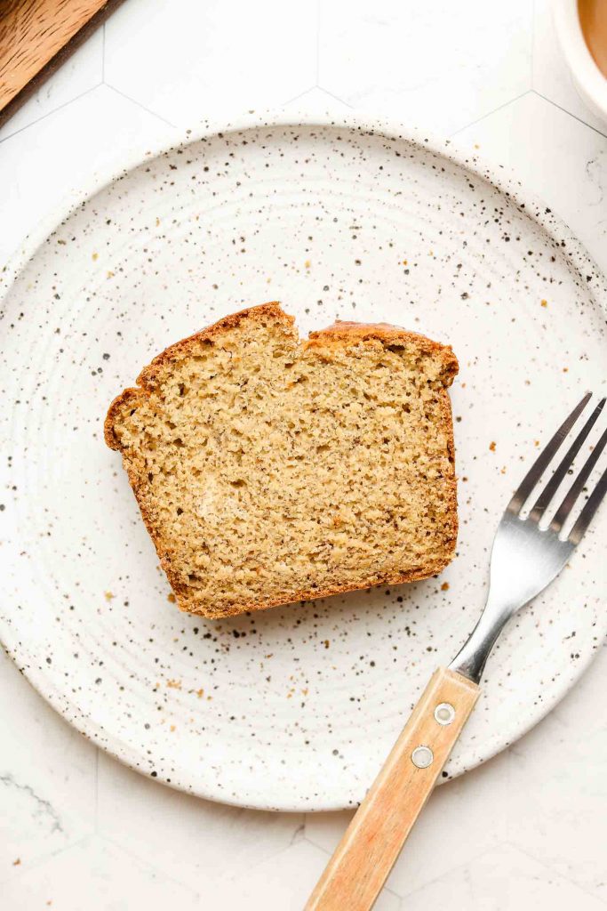 fluffy banana bread on a white speckled plate with a fork on the right side