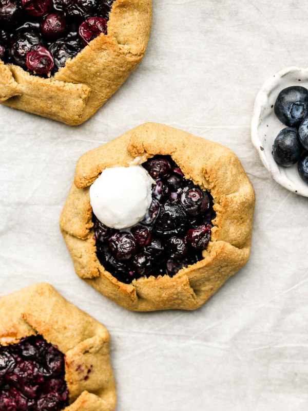 3 mini blueberry galettes on parchment paper with coconut ice cream on top