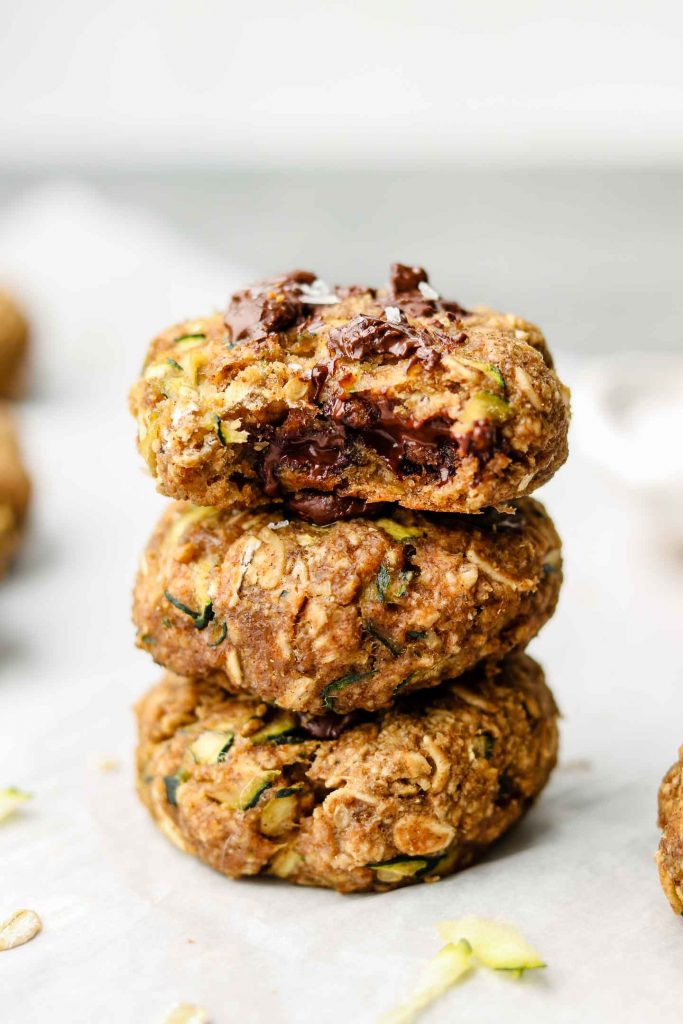 close up shot of a stack of zucchini chocolate chip oatmeal cookies with a bite taken out of the top cookie