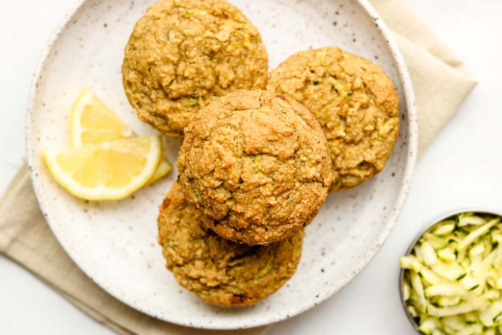 lemon zucchini muffin on a white speckled plate