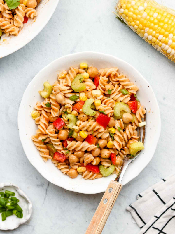 fresh bbq pasta salad with lots of veggies on a white plate and fork