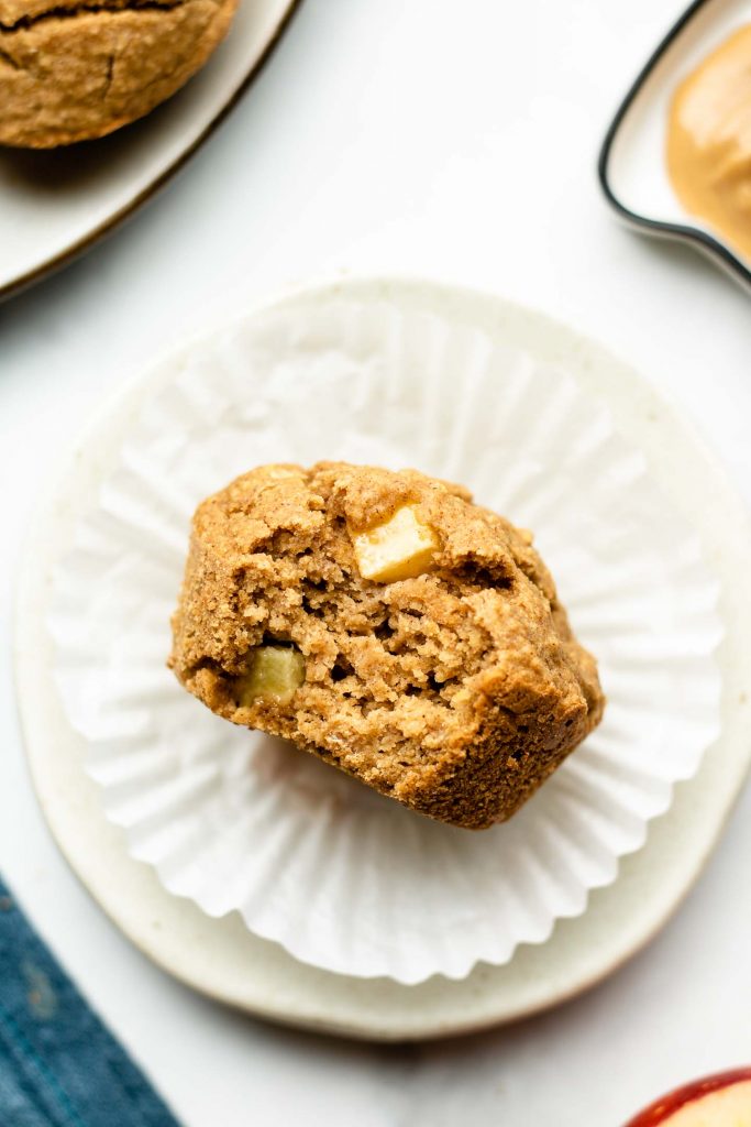 healthy apple cinnamon oatmeal muffin on a small white plate with a bite taken out of it