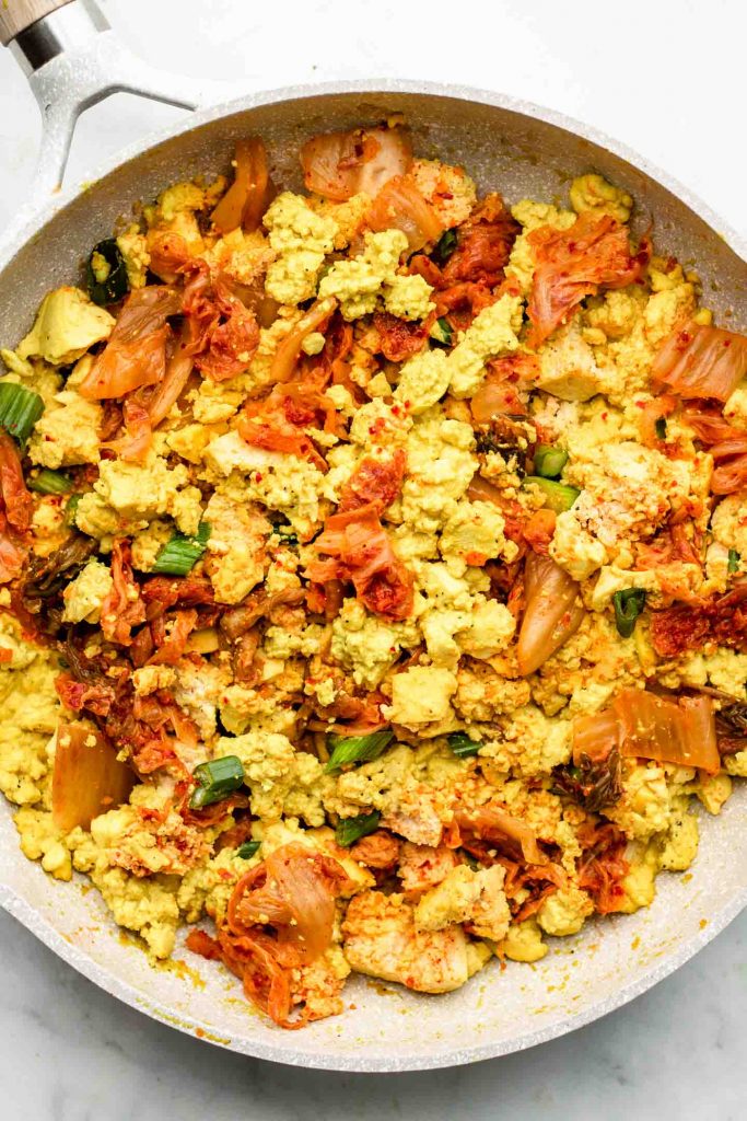 scrambled tofu with kimchi in a white speckled pink pan