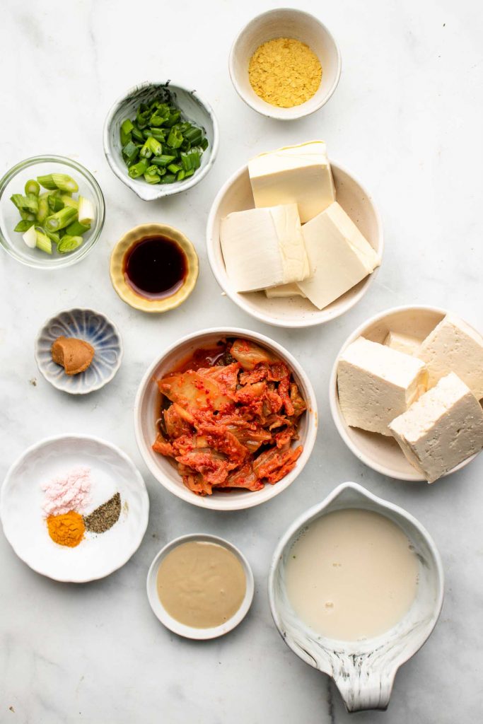 ingredients for kimchi tofu scramble in bowls on a marble backdrop