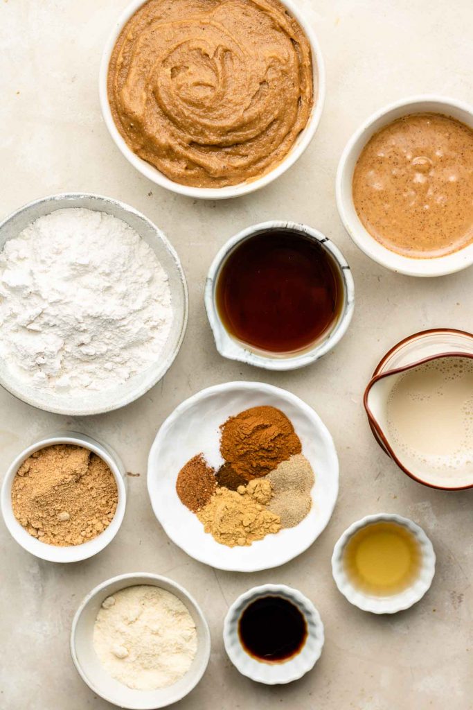 vegan chai spiced cupcake ingredients in white bowls on a beige backdrop