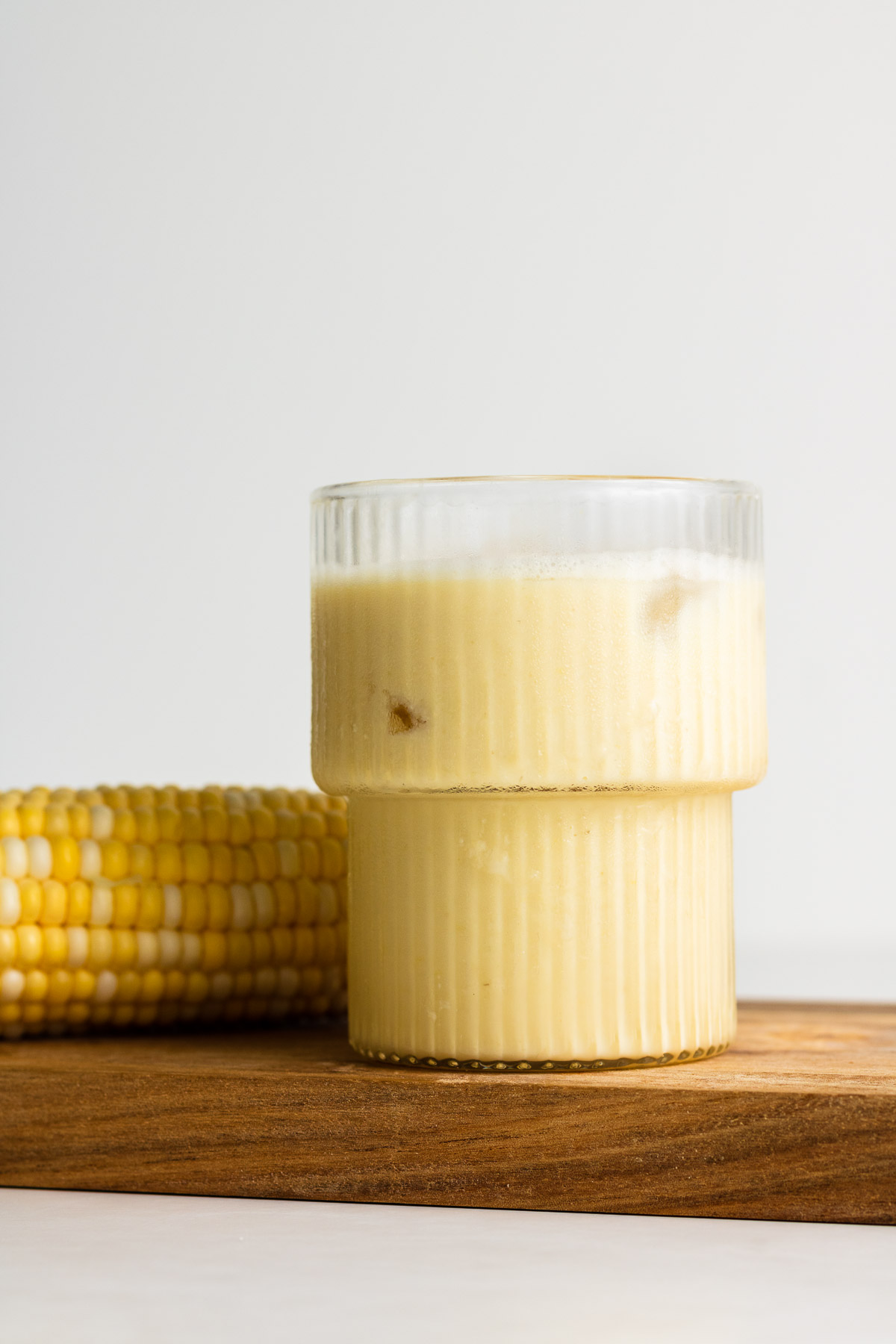 corn milk in a mushroom cup with cob beside it